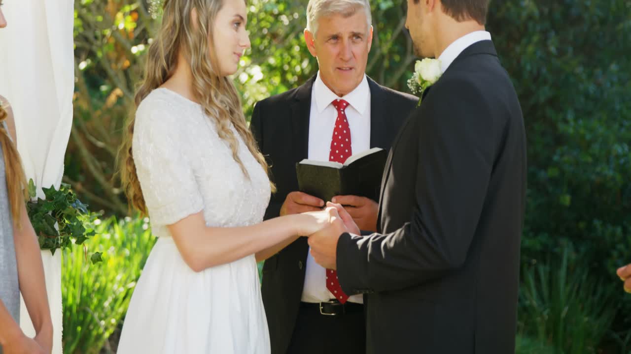 la novia y el novio felizmente intercambiando anillos mientras la bendición por el sacerdote 4k 4k