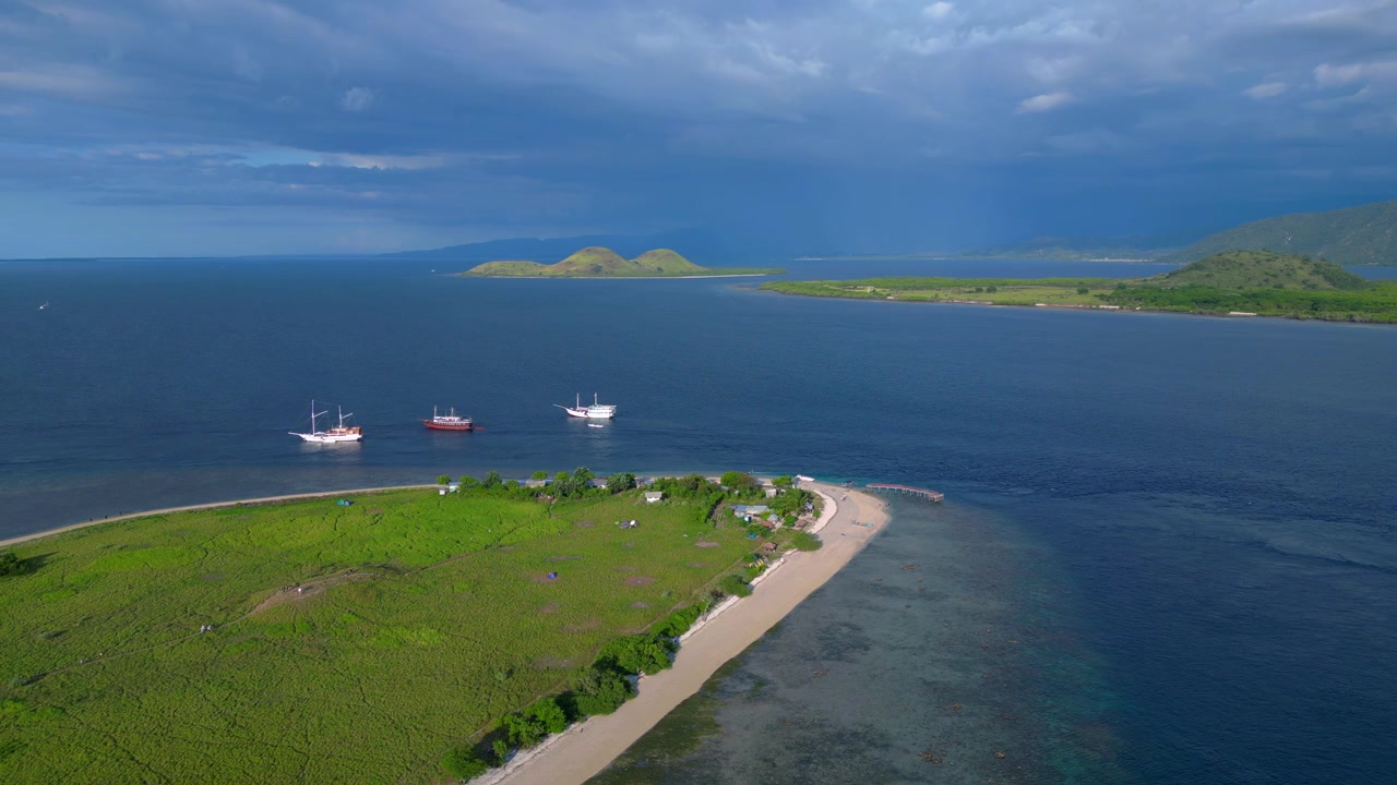 Barche tradizionali ancorate vicino a un'isola verde in una remota baia indonesiana con cielo nuvoloso. Incredibile vista aerea, panorama statico da drone in hovering.
