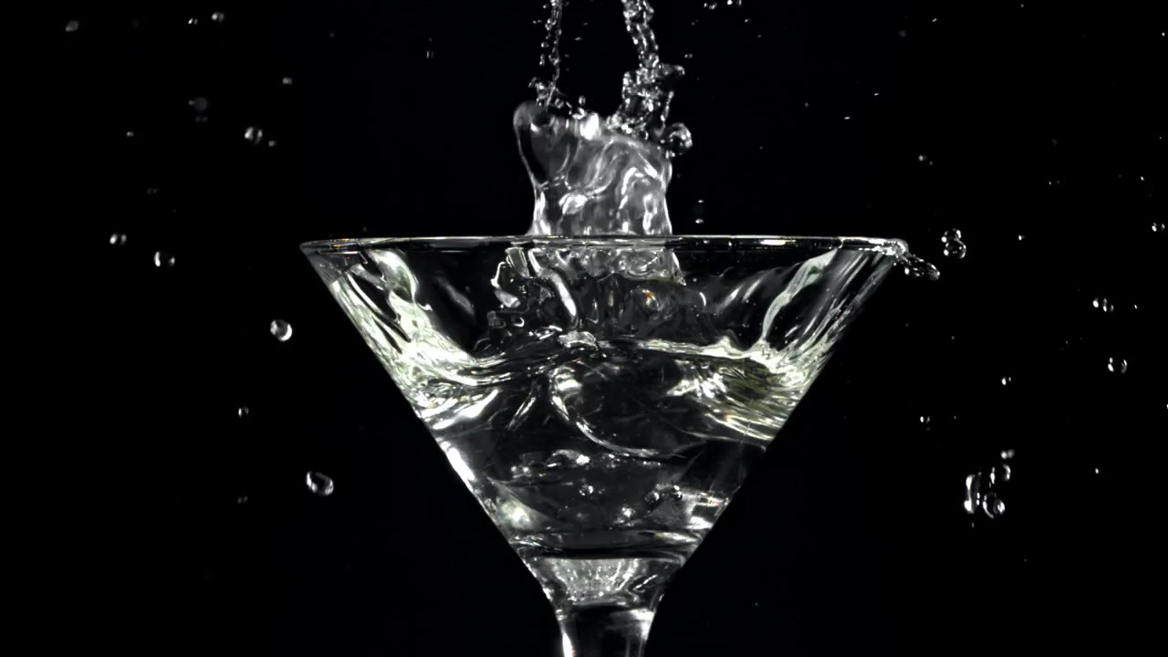 Cubetti di ghiaccio che cadono in un bicchiere da Martini con schizzi al rallentatore