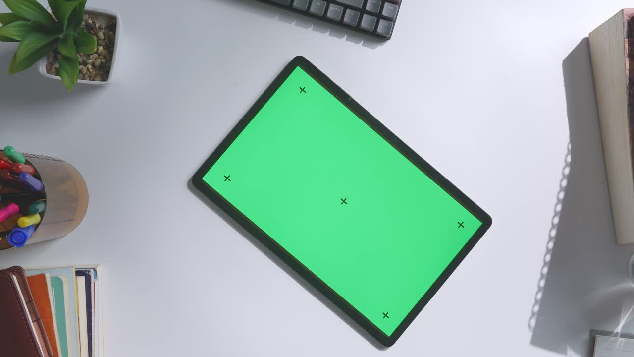 vista de arriba hacia abajo de una computadora portátil con pantalla verde simulada pantalla chromakey en un escritorio de oficina de madera al lado de la libreta con bolígrafos, gafas y un vaso de agua.
