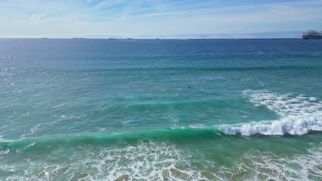waves crash gently on praia de são torpes beach, calm and clear springtime day