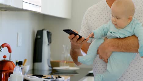 Vater-Und-Kleiner-Junge-Benutzen-Mobiltelefon-In-Der-Küche-4k