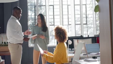 diverse colleagues with documents and tablet discussing work in office, copy space, slow motion