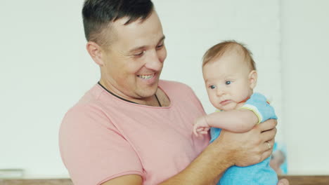 padre joven feliz con su hijo en sus brazos sonriendo en casa