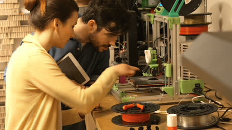 male and female graphic designer interacting over a machine