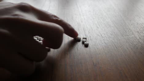 many, white tablets on table, female hand counting pills