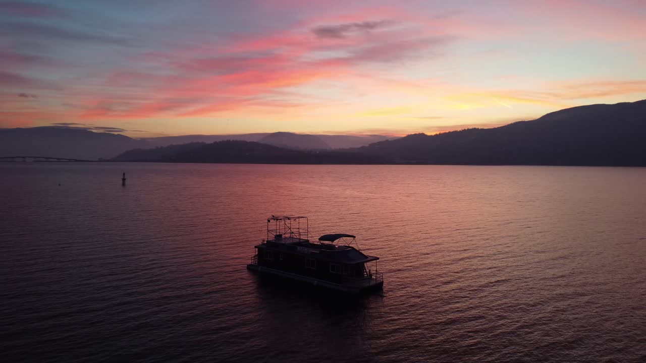 drone giratorio disparó alrededor de un barco en el agua de kelowna lago okanogan puesta de sol