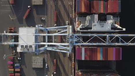 Overhead-View-Of-Gantry-Crane-Moving-Cargo-Containers-With-Trucking-Services