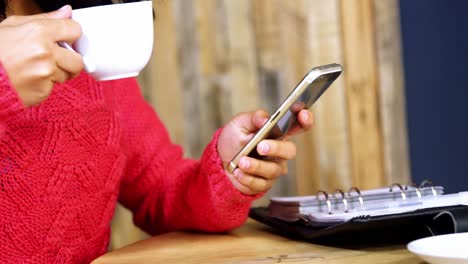 beautiful woman using mobile phone while having coffee