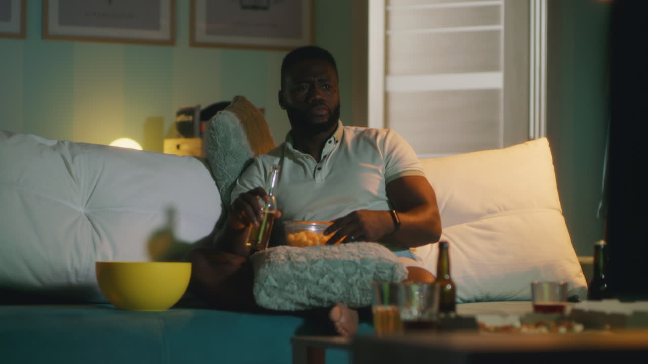 Man Watching TV at Home with Beer and Popcorn