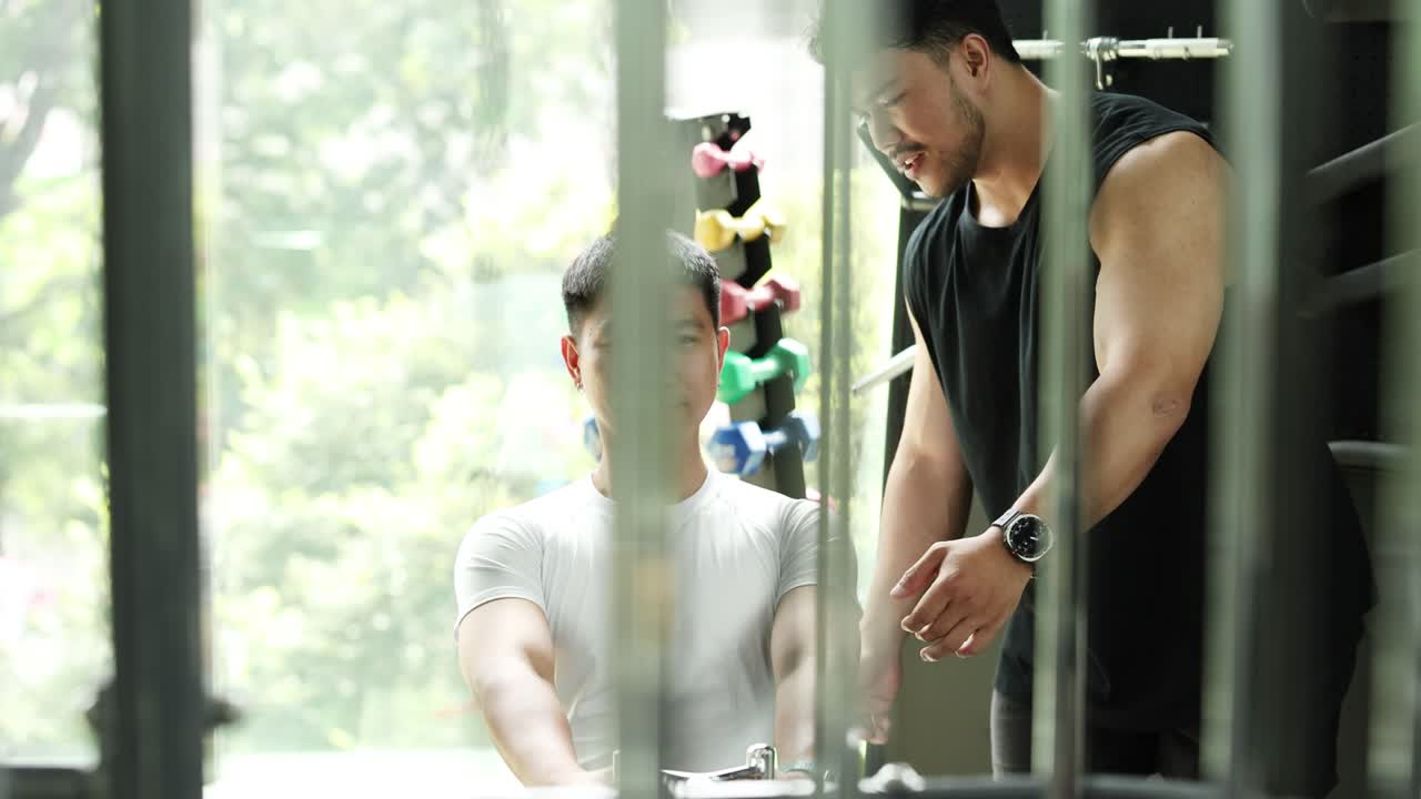 A trainer guides a client through exercises in a well-lit gym, emphasizing technique and form amidst modern equipment