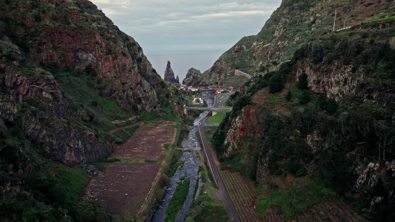 Aerial view of a valley with a river and roads, surrounded by mountains