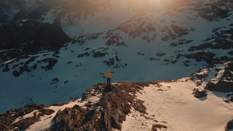 Person-standing-in-front-of-two-wodden-cabins-at-sunrise