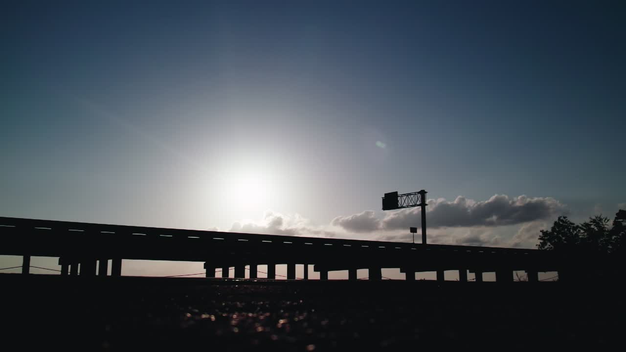 Powerful low angle shot of a silhouette vehicle driving into the setting sun, Luisiana, USA