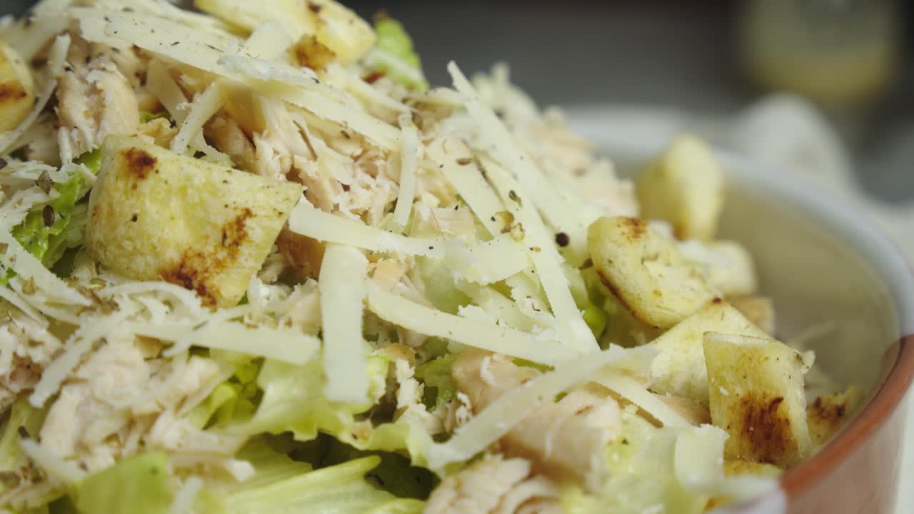 primer plano de una ensalada césar bien chapada con queso rallado encima