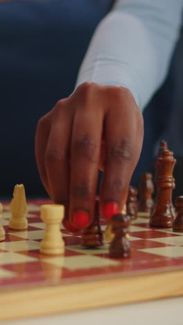 vertical video: close up of black woman moving chess pieces on board