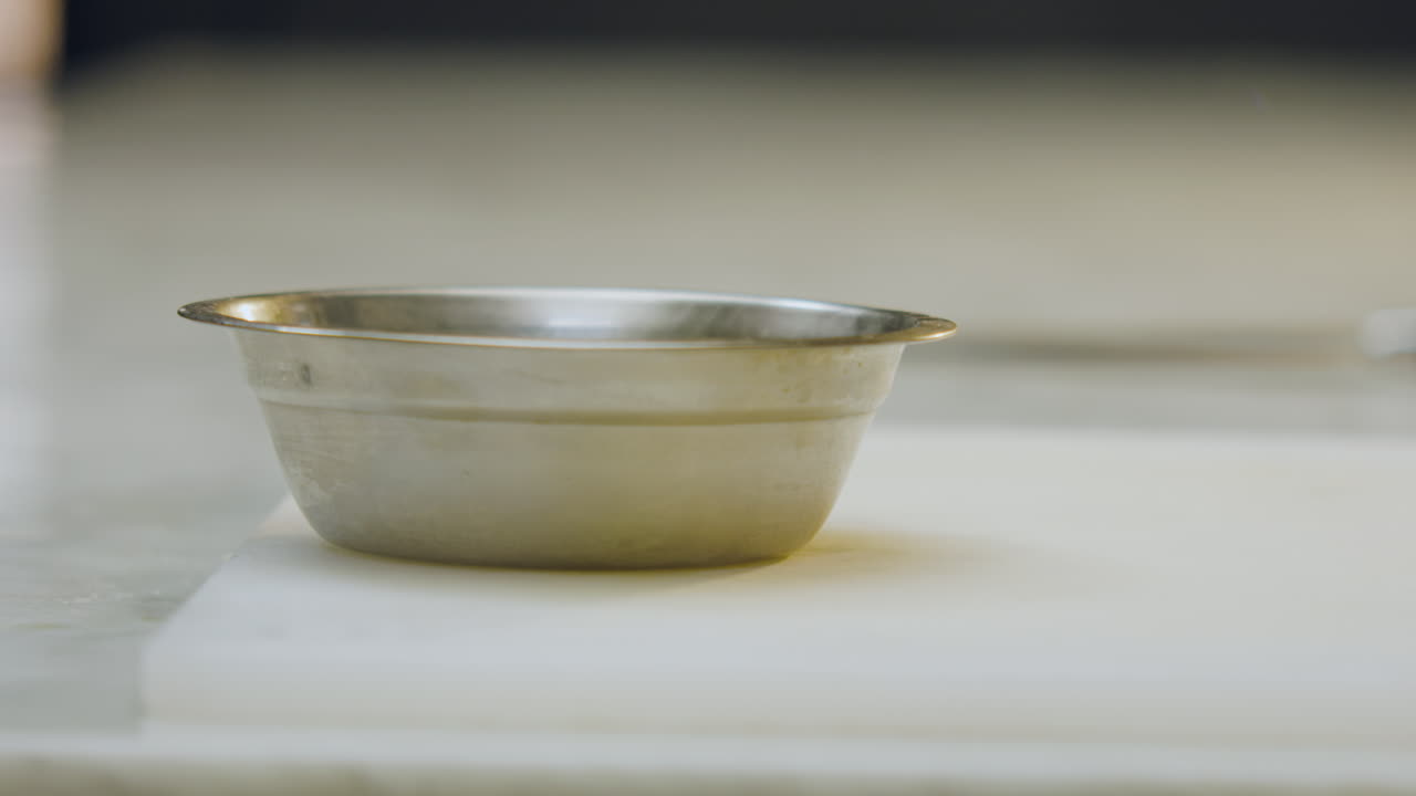 Close-up of an aluminum mold placed on a chopping board. The clip highlights the metallic texture, the culinary environment, and the preparation prior to cooking or baking processes