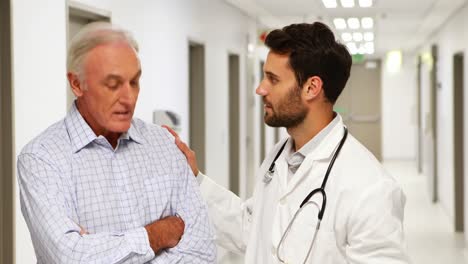 el médico y el paciente discutiendo sobre el clipboard en el pasillo