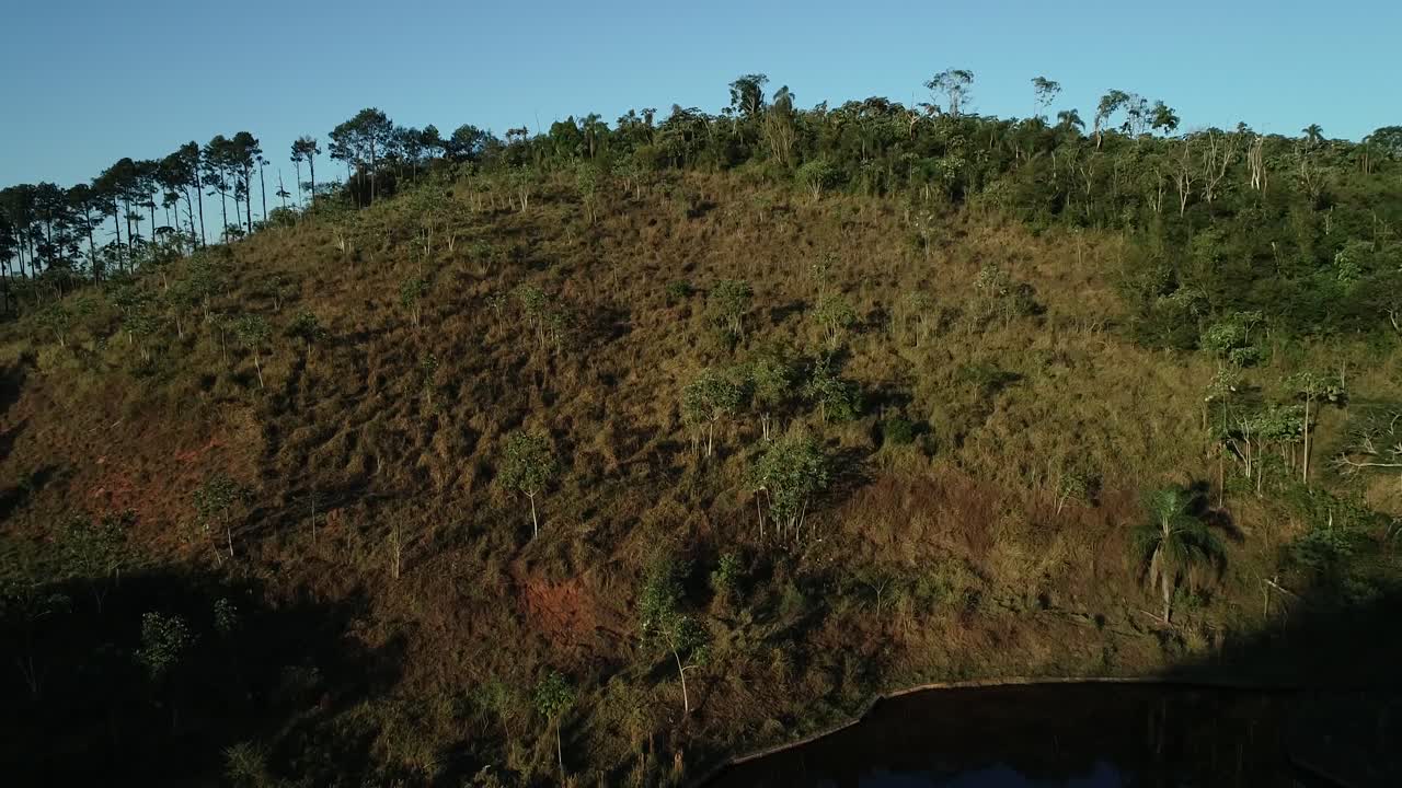 Side shot shot with drone of beautiful lush green landscape, lake at the bottom of the image, in 4K resolution, peace, calm, tranquility
