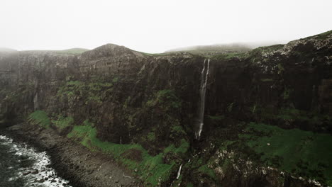 Big-Waterfall-Gushes-Over-Lush-Green-Cliffside-Into-The-Sea,-Talisker-Bay-Scotland