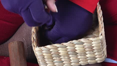 putting finishing touches on a water hyacinth woven basket with a knife