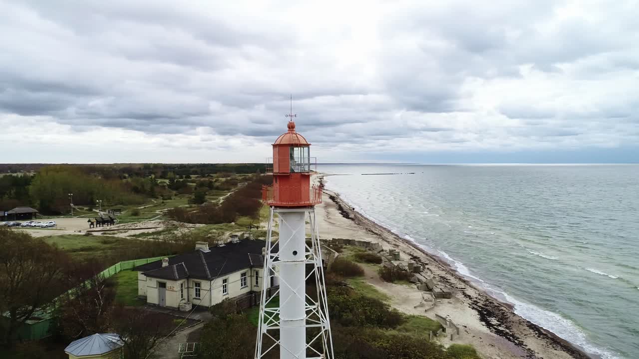 Un drone riprende le nuvole sopra l'iconico Faro di Pape, spiaggia battuta dal vento, Lettonia.