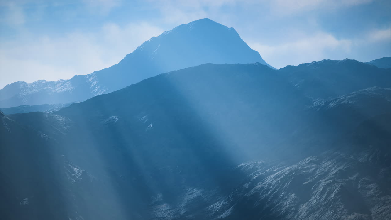 霧に包まれた山々に、雲間から太陽の光が差し込んでいます。