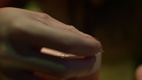 Extreme-close-up-of-frothy-tropical-cocktail-being-dressed-with-rosemary-leaves-filmed-in-slow-motion