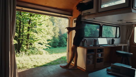 person standing in camper van doorway overlooking forest