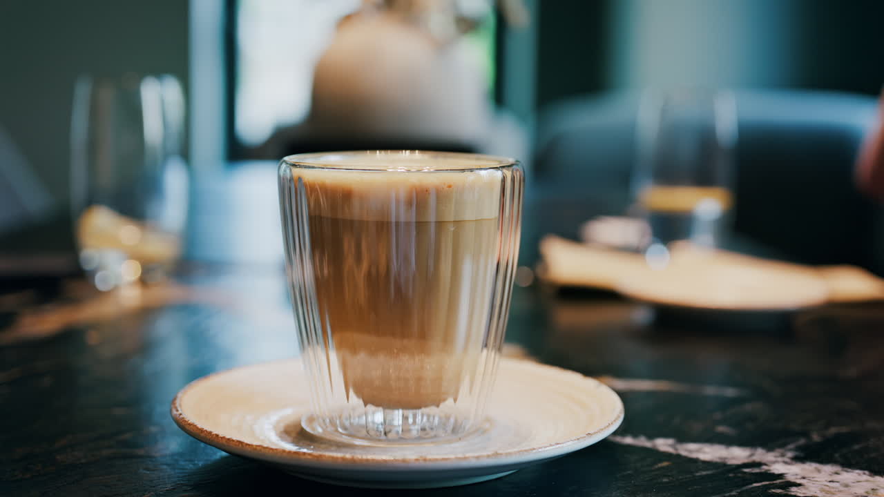 Close up of a glass cup with a latte at a cafe