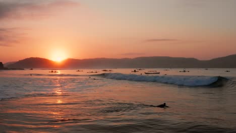 sunrise at the surf spots of gerupuk in lombok, with a view on the bay with the fishing boats and surfers