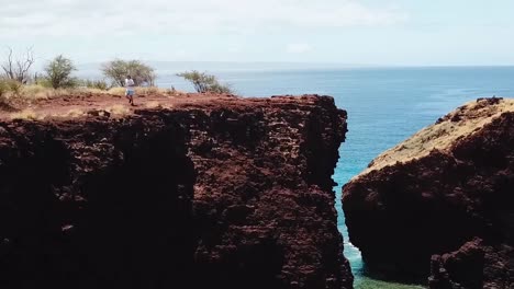 drone aerial man running on cliffside beach hawaii