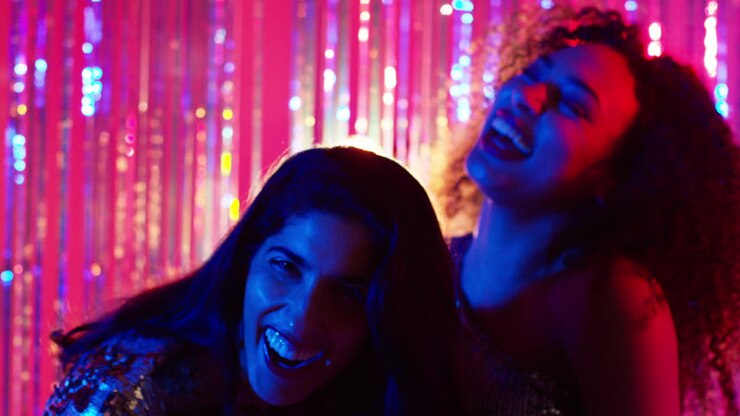 Ritratto di due amiche che si divertono a ballare in un bar o discoteca con luci scintillanti 4