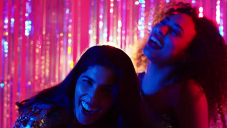 portrait of two women friends having fun dancing in nightclub bar or disco with sparkling lights 4