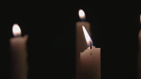 four white candles lit and a fast pan across them in slow motion