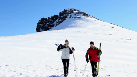 sporty couple walking down the ski slope