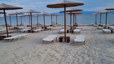 Playa-Vacía-Con-Tumbonas-Y-Sombrillas-De-Madera-En-El-Mar-Mediterráneo