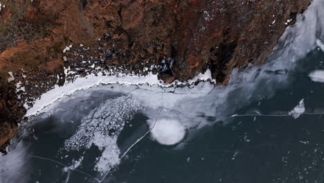 rising aerial of colorful rocky iceland landscape along frozen beach, daytime