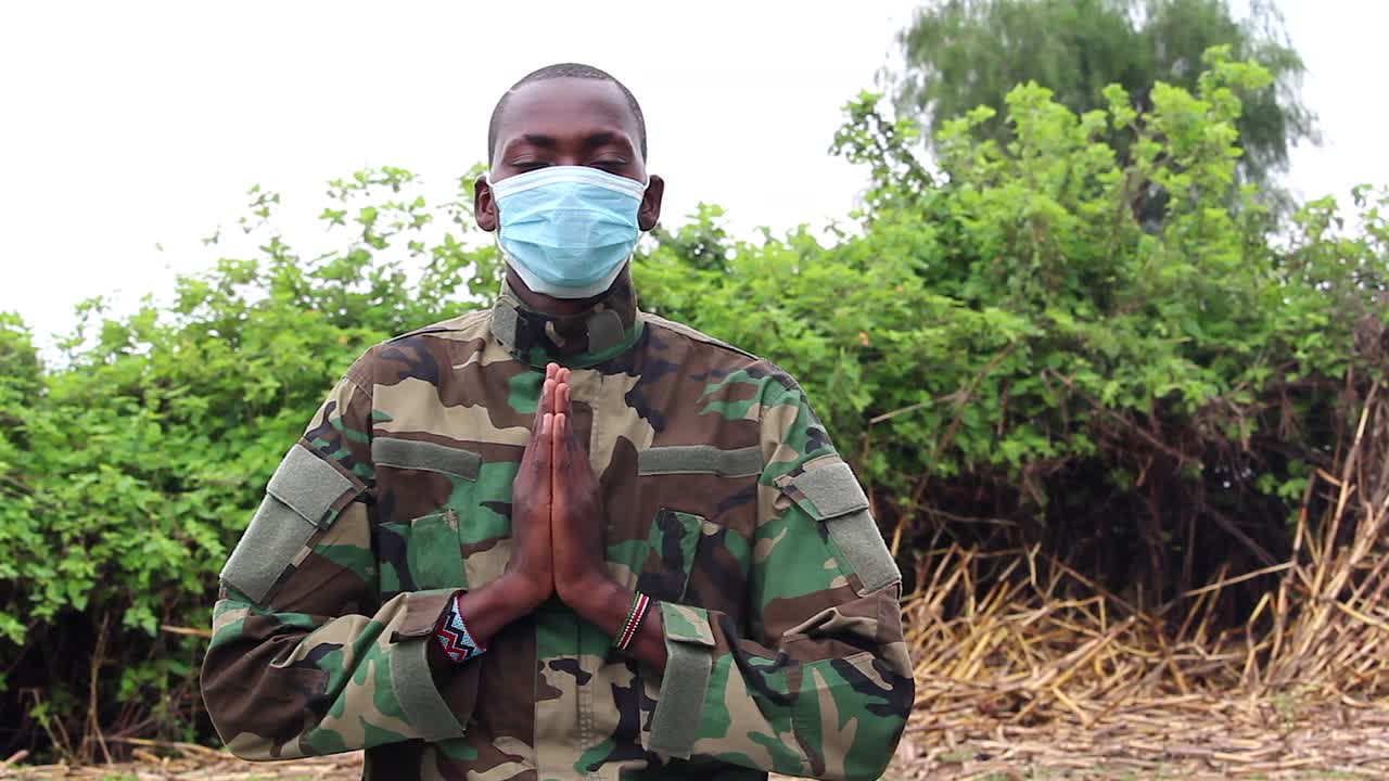 Soldato africano che prega con la mascherina anti-Covid indossata.