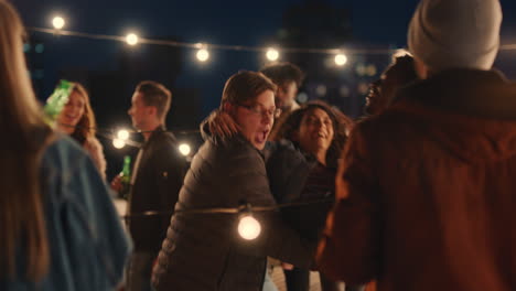happy multiracial friends having fun dancing playfully together enjoying rooftop party at night laughing celebrating friendship