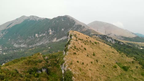 aerial dolly in: drone flying towards a spectacular rocky mountain system with great biodiversity in south of italy