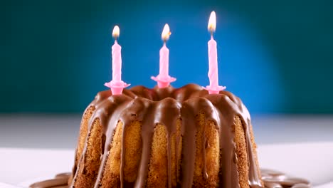 burning pink birthday candles on marble cake with chocolate nougat icing