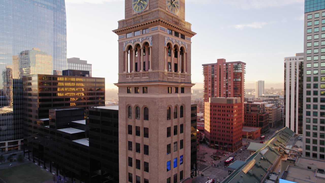 vista aérea de drones volando hacia arriba mostrando la estructura emblemática de la torre del reloj de lannies en el centro de denver colorado durante la puesta de sol de la hora dorada