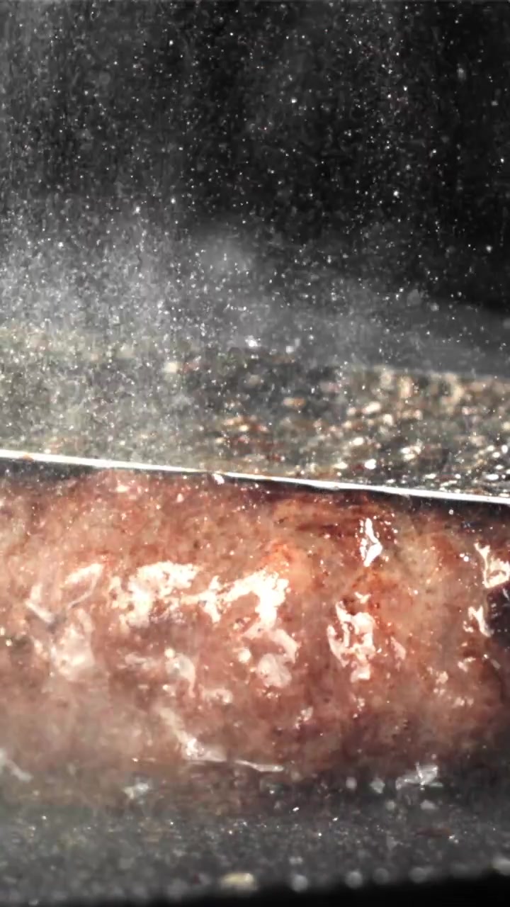 Nærbillede af stegende pølse på en varm pande med sydende damp