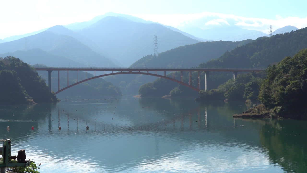 Niji no Ohashi Bridge with Honma no Atama Ridge on the Background. Lake Water mirroring the bridge and the ridge. It is located between Kiyokawa Village and Sagamihara City of Kanagawa, Japan