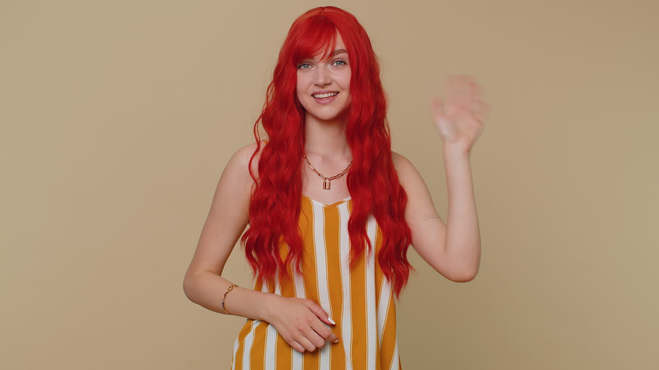 은 머리 여자 는 카메라 에 친절 하게 미소 짓고 손 을 흔들며 인사 나 작별 인사를 하고 환영 한다