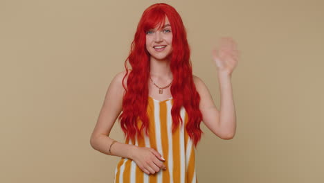 Redheaded-woman-smiling-friendly-at-camera-and-waving-hands-gesturing-hello-or-goodbye,-welcoming