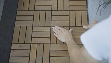 unrecognizable person installing wooden decking tiles at the terrace