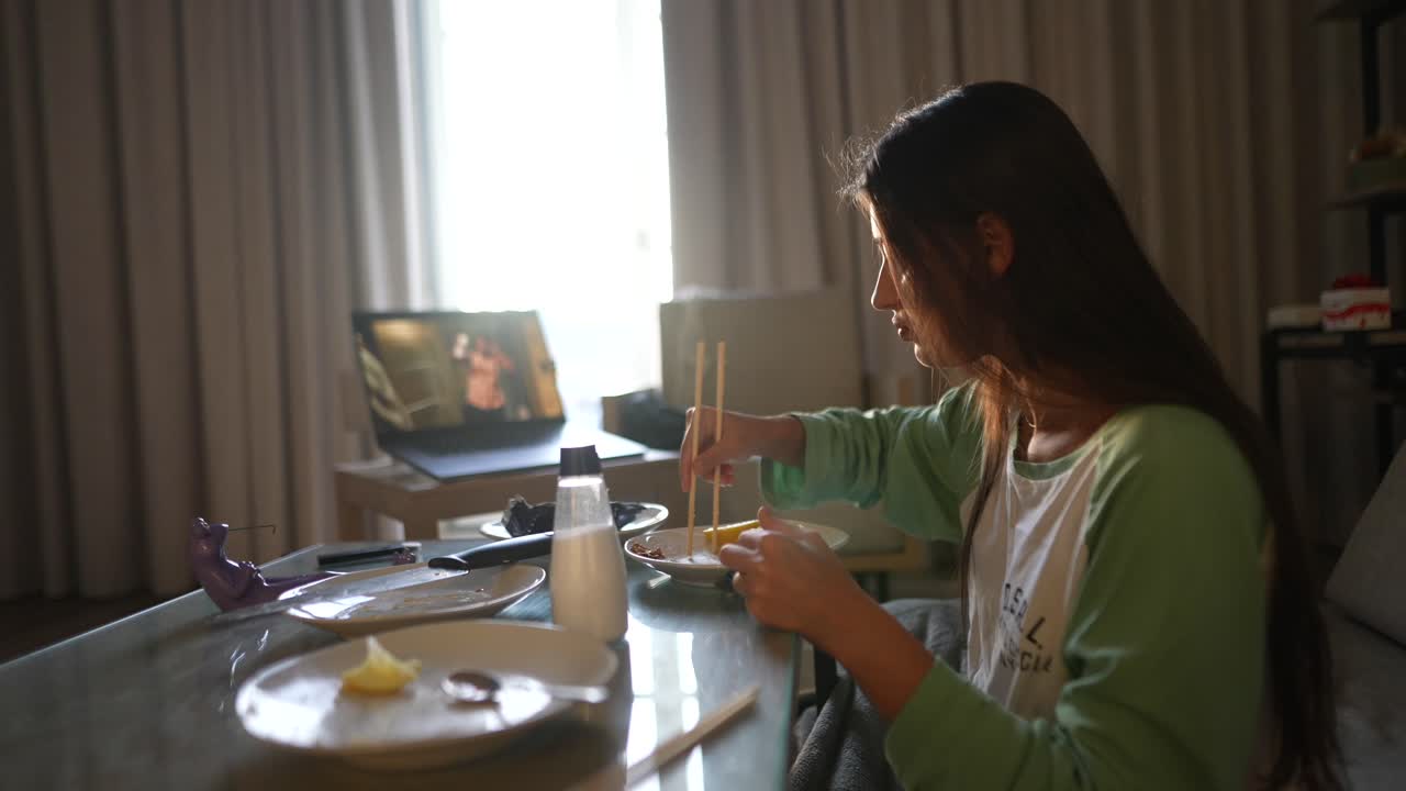 una adolescente cenando y viendo una llamada de video