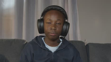 boy at home sitting on sofa wearing headset playing video game 1